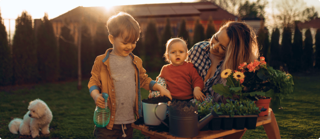 A family gardening while their home with rooftop solar panels can be seen in the background
